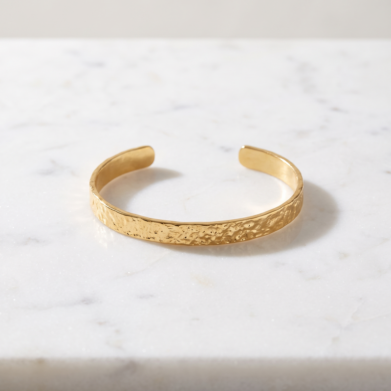 Hammered gold open cuff bracelet on white marble