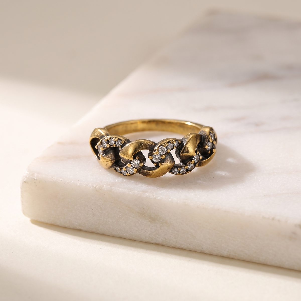 Vintage gold chain link ring, lying on white marble