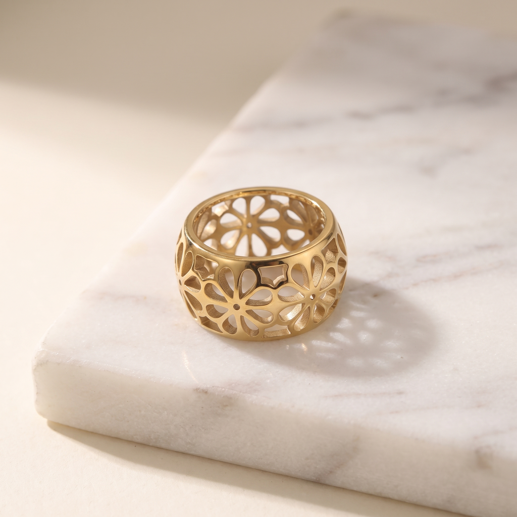 Gold petal flower ring in stainless steel, lying on white marble