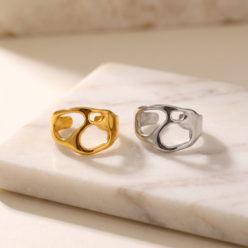 Angular geometric open ring in titanium steel, lying on white marble