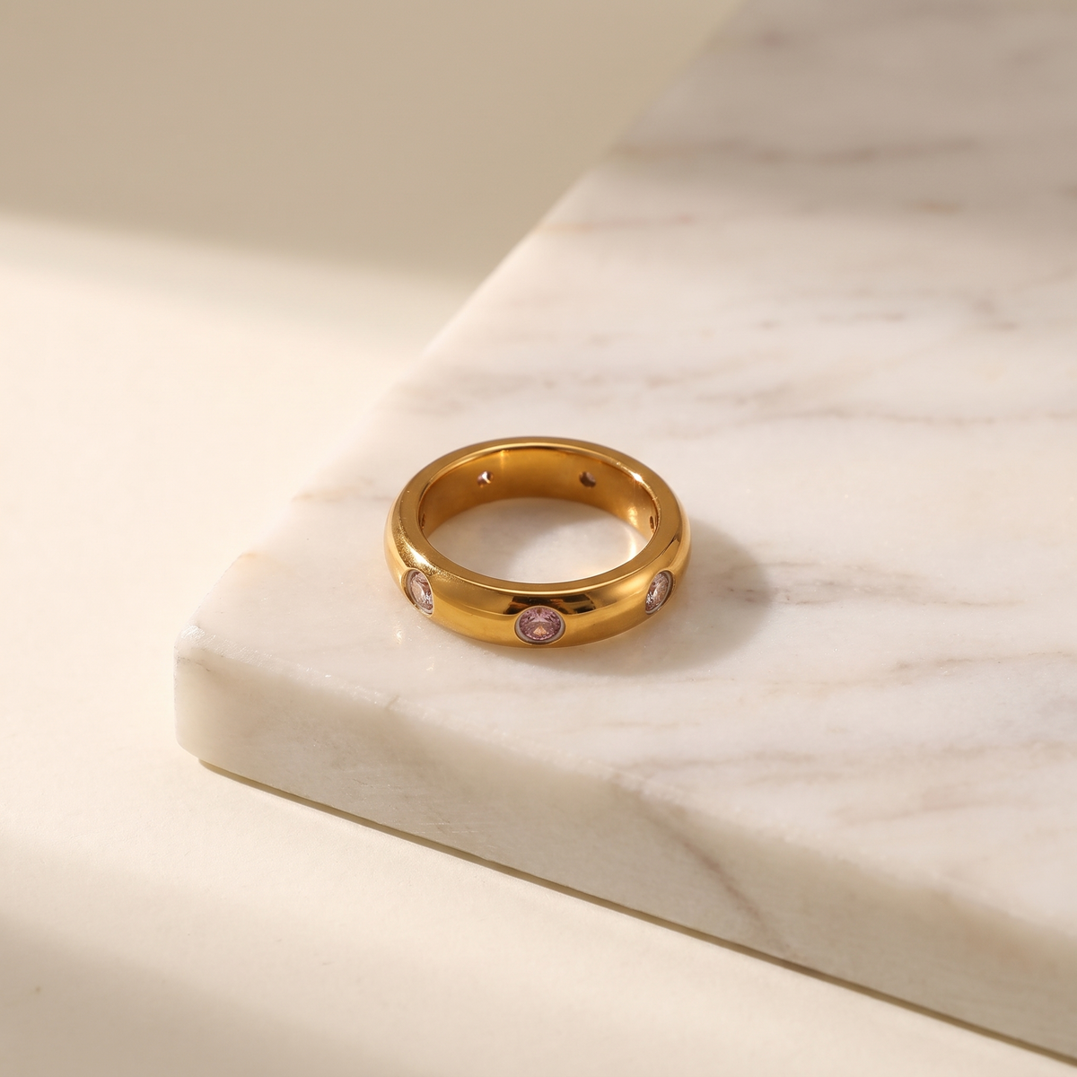 Vintage gold ring set with a cut zircon stone, lying on white marble
