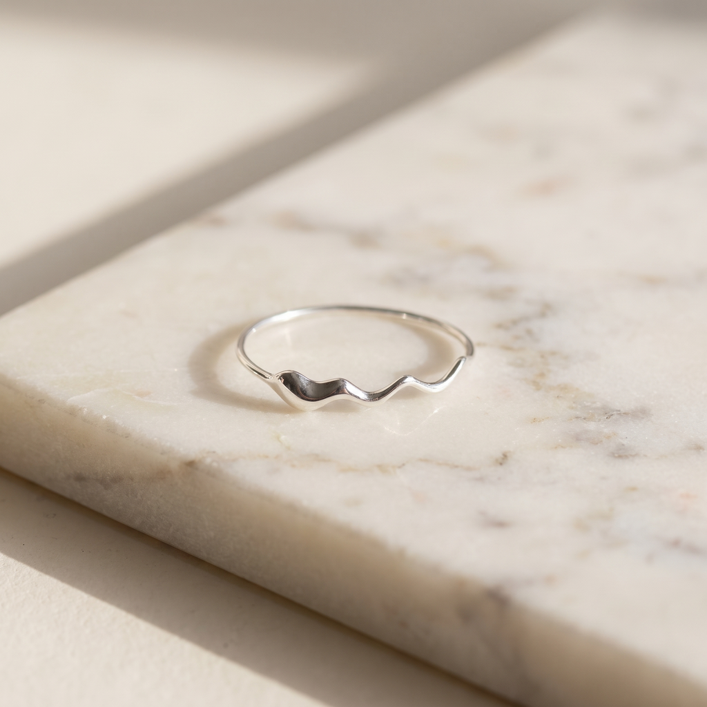 Sterling silver wave ring, lying on white marble