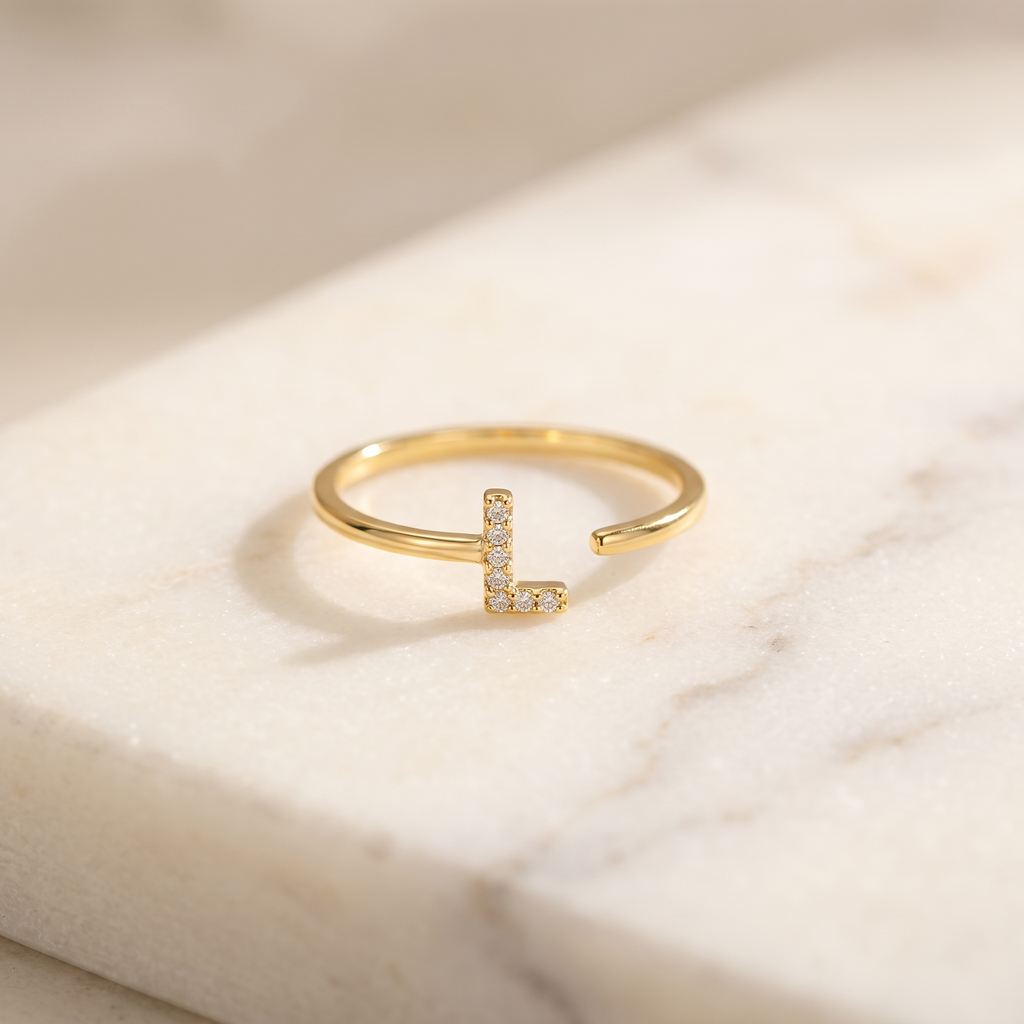Gold initial letter ring set with zircon, lying on white marble