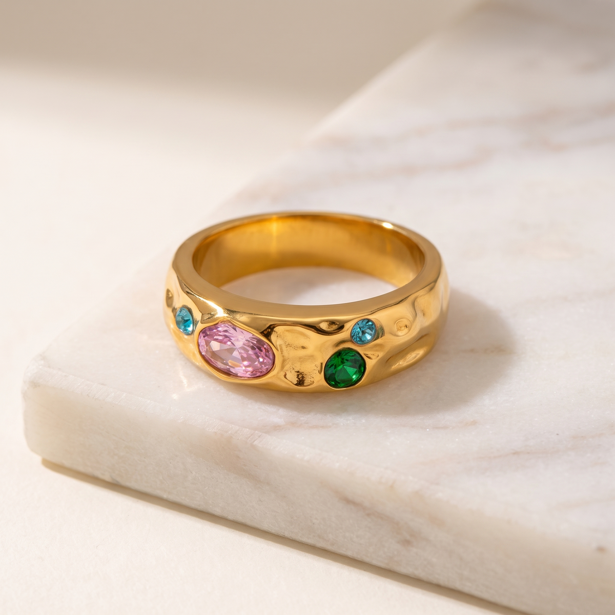Pave geometric gold ring set with zircon, lying on white marble