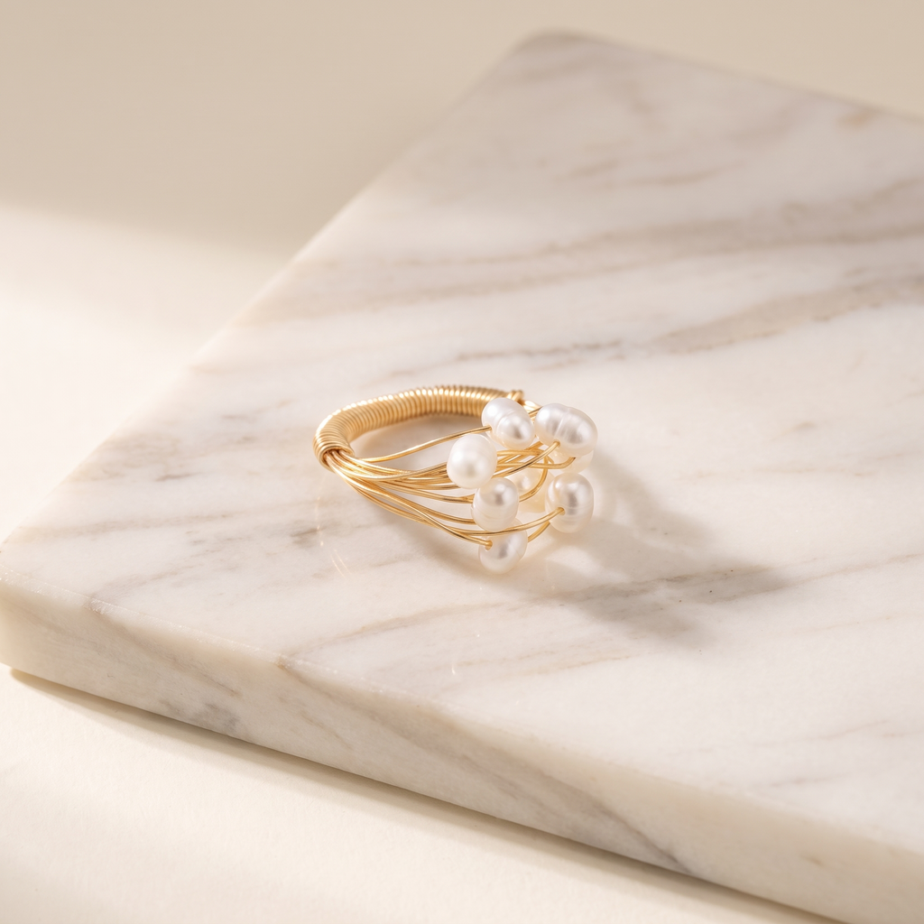 Freshwater pearl wrapped in gold wire ring, lying on white marble