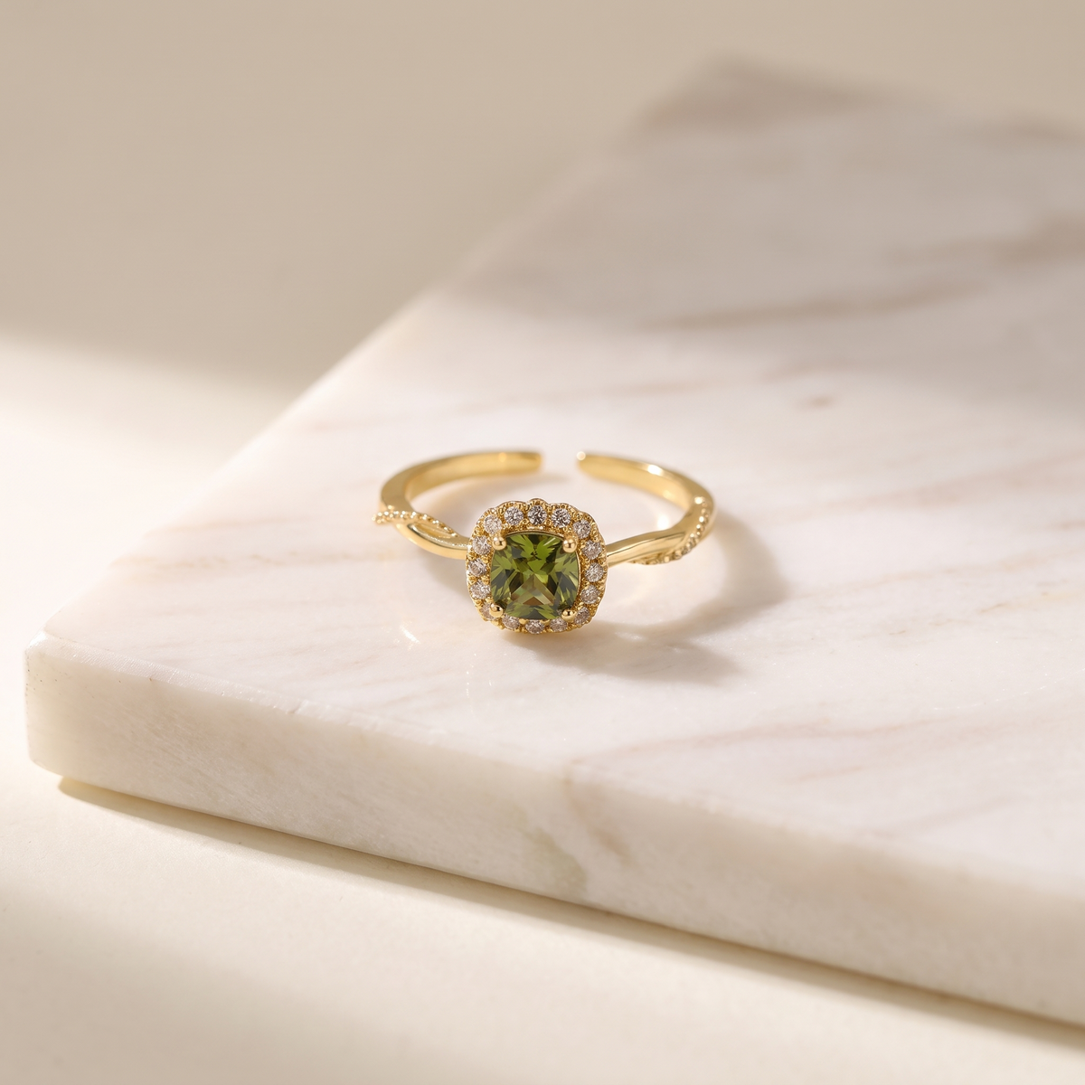 Olive green zircon open ring in gold, lying on white marble