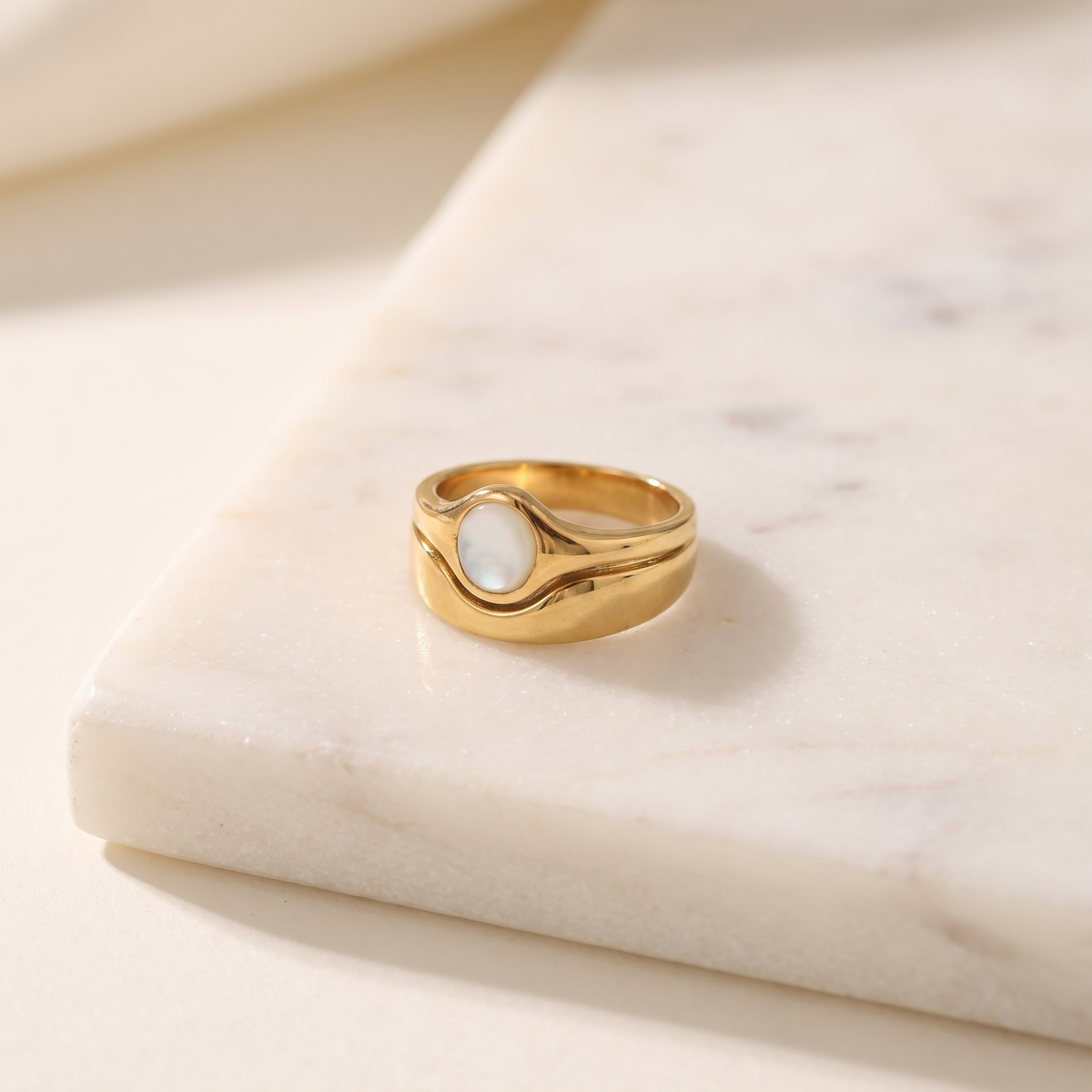 Mother-of-pearl gold signet ring, lying on white marble