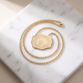 Gold initial letter necklace on white marble