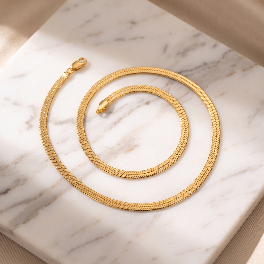 Flat gold snake chain necklace on white marble