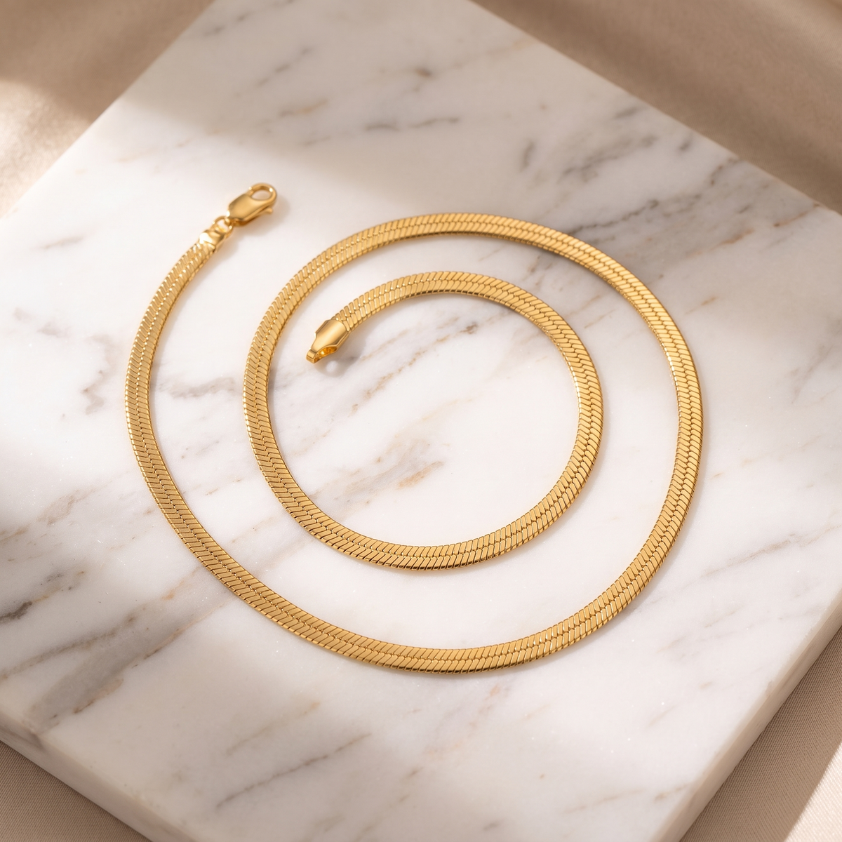 Flat gold snake chain necklace on white marble