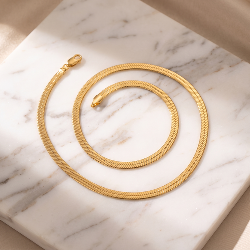 Flat gold snake chain necklace on white marble