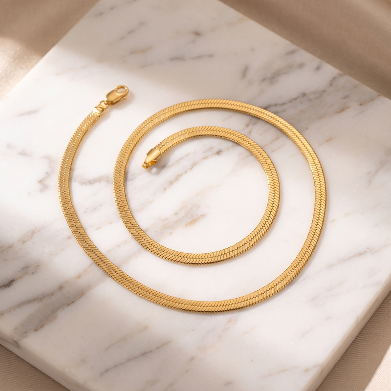 Flat gold snake chain necklace on white marble