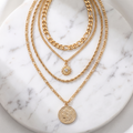 Layered gold coin necklace on white marble