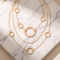 Gold layered necklace with open circle pendant on white marble