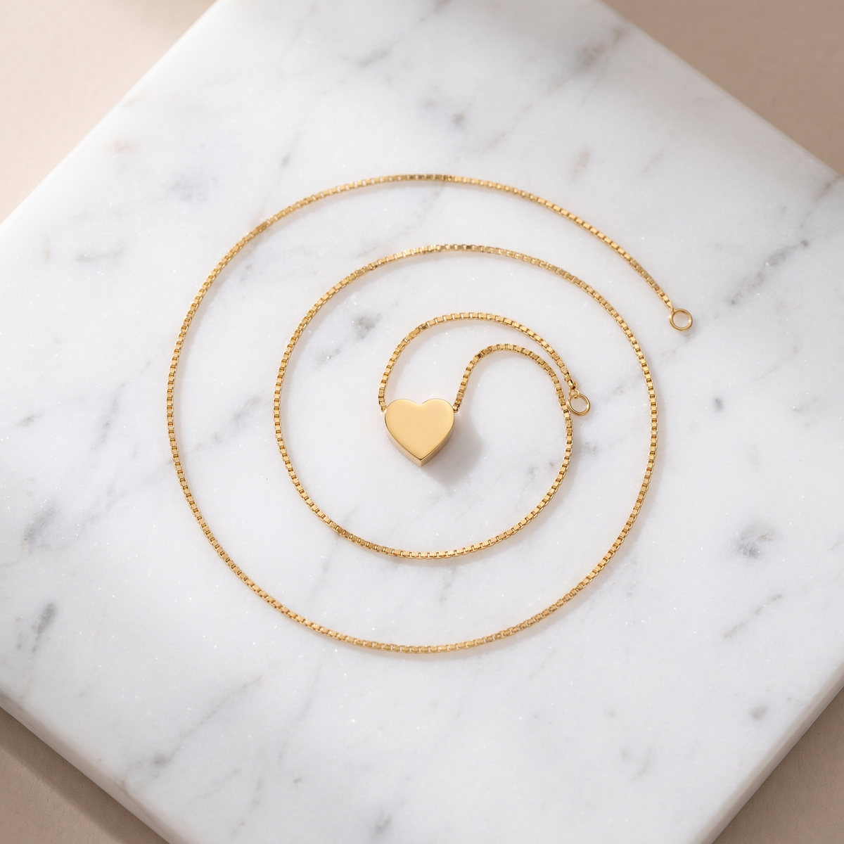 Small gold heart pendant necklace on white marble