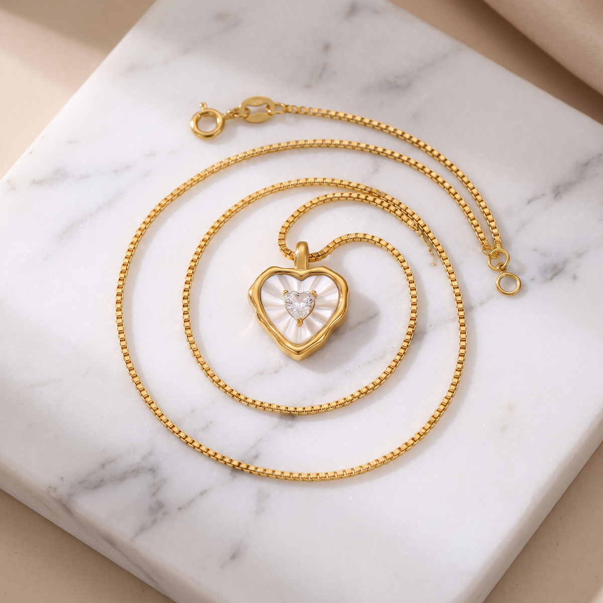 Mother-of-pearl heart pendant necklace in gold on white marble