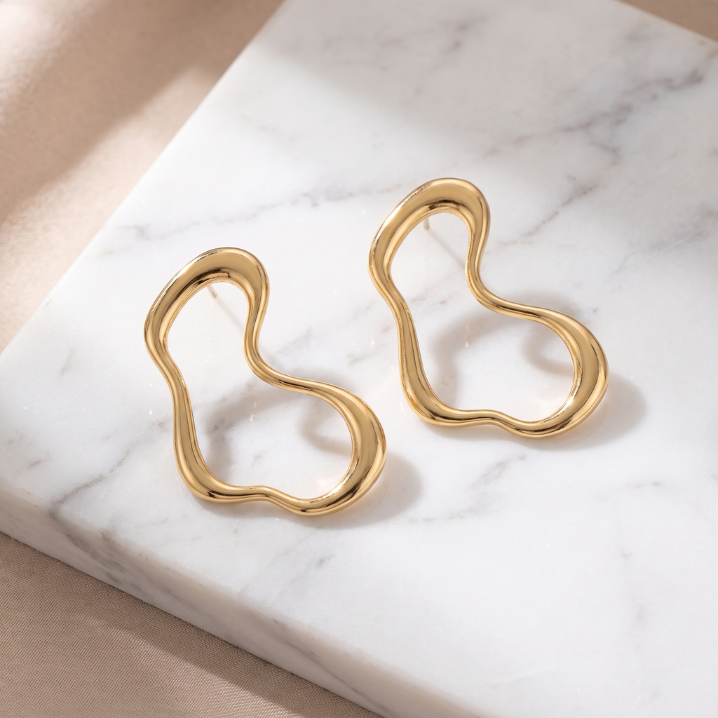 Sculpted geometric gold earrings on white marble