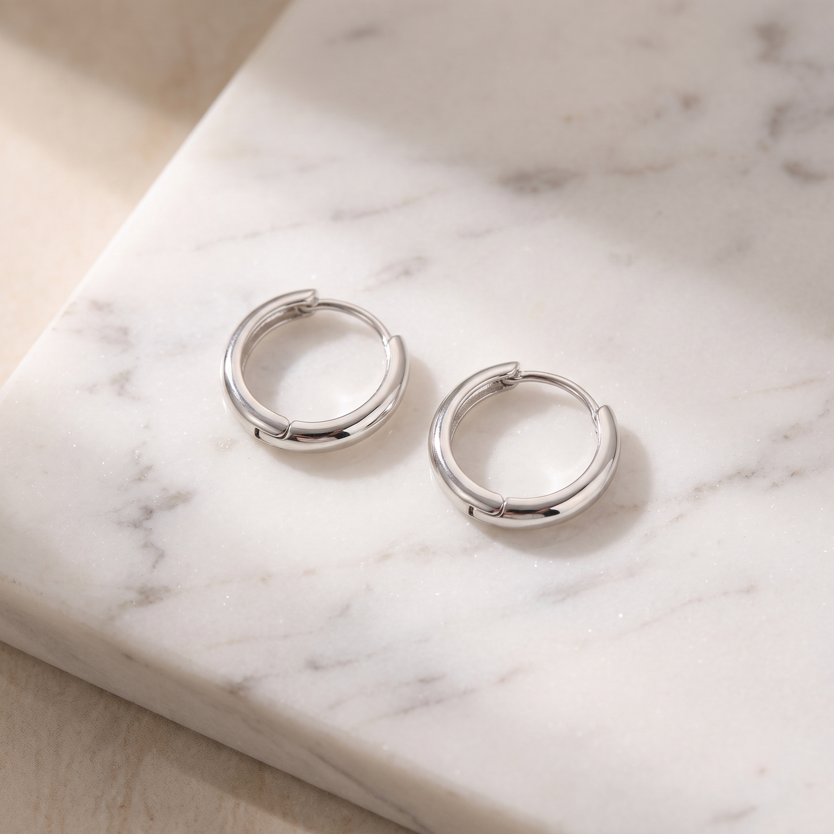 Sterling silver hoop earrings on white marble