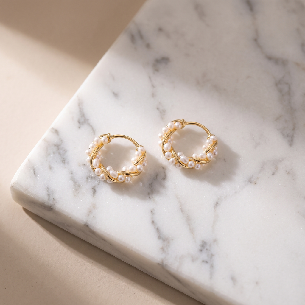 Gold pearl hoop earrings on white marble