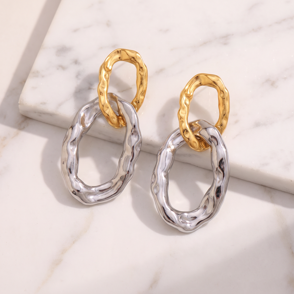 Hammered gold hoop earrings on white marble
