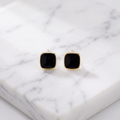 Black square drop earrings in gold on white marble