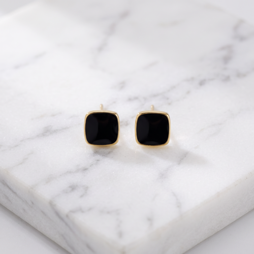 Black square drop earrings in gold on white marble