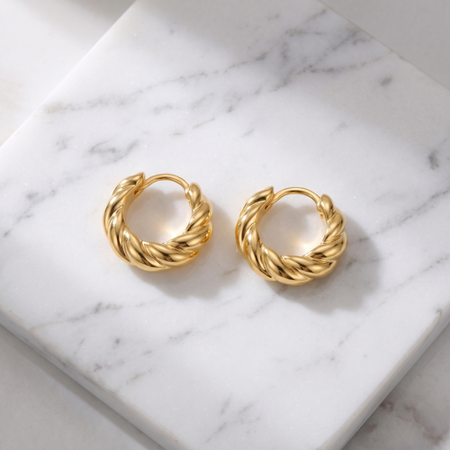 Croissant twist gold hoop earrings on white marble