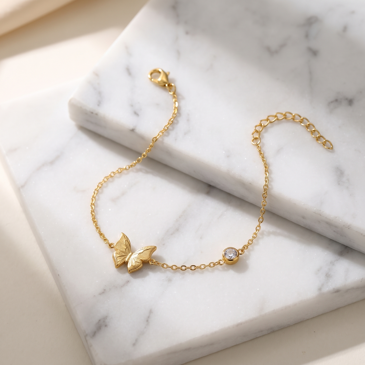 Gold butterfly chain bracelet on white marble