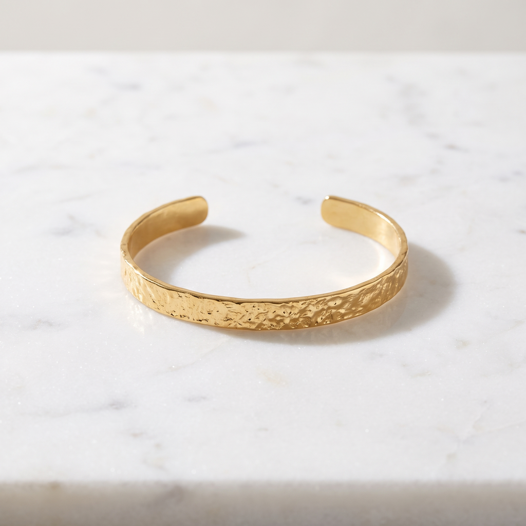 Hammered gold open cuff bracelet on white marble