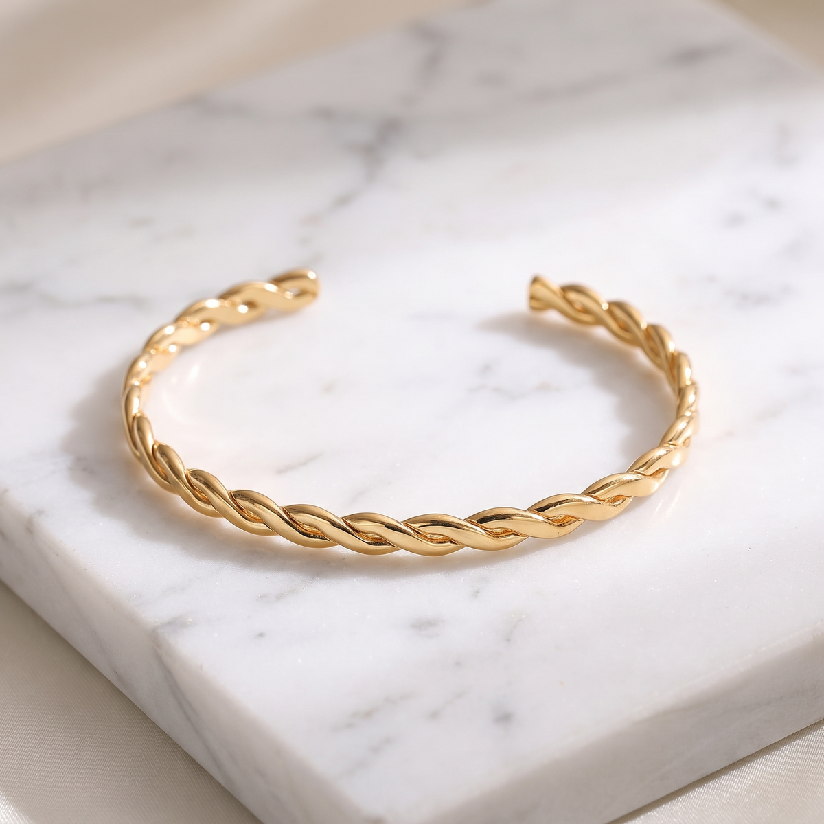 Twisted rope gold cuff bracelet on white marble