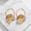 Gold petal drop hoop earrings on white marble